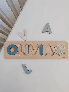 a wooden name puzzle with the word oliva spelled in blue and white letters