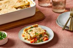 a table topped with plates and bowls filled with food next to a casserole dish