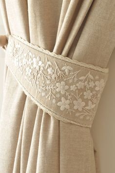 the back of a beige curtain with white flowers and leaves on it's side