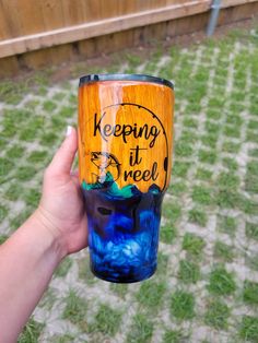 a hand holding a blue and yellow tumbler with the words keeping it free on it