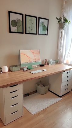 a desk with drawers and a laptop on it in front of two pictures hanging on the wall