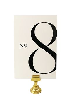 the number 8 is placed on top of a card with a gold postcard holder