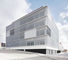 the building is white and has many windows on each side, along with an empty parking lot