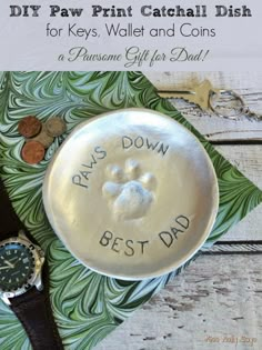 a dog's paw print on a dish next to a watch