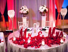 the table is decorated with candles and red rose petals for an elegant centerpieces