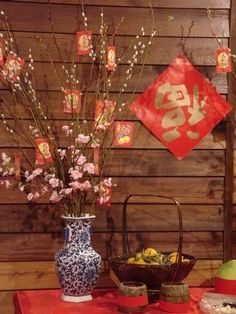 a table topped with vases filled with flowers next to a red cloth covered wall