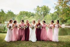 a group of women standing next to each other in front of a lake and trees