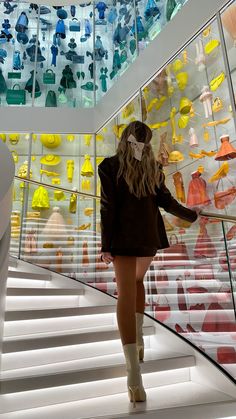 a woman walking up some stairs in front of a glass case with many different colored objects