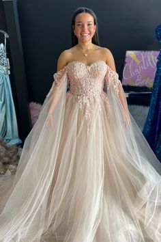 a woman standing in front of a bed wearing a wedding dress