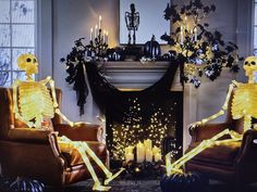 two skeletons sitting on chairs in front of a fire place with candles lit up behind them