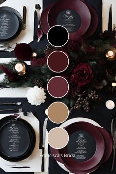 the table is set with black and white plates, silverware, red flowers and candles