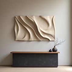 a vase sitting on top of a wooden table next to a wall mounted art piece