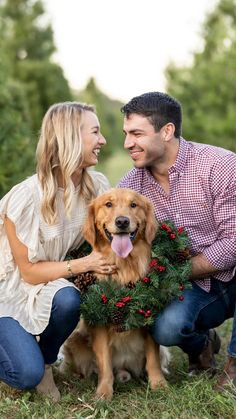 a man and woman sitting next to a dog wearing a wreath