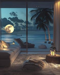 a living room filled with furniture and a large window overlooking the ocean at night time