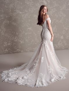 a woman in a wedding dress posing for the camera with her back to the camera