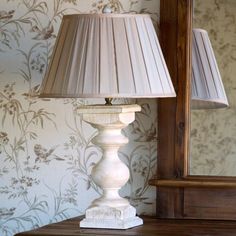 a lamp sitting on top of a wooden table next to a wallpapered wall