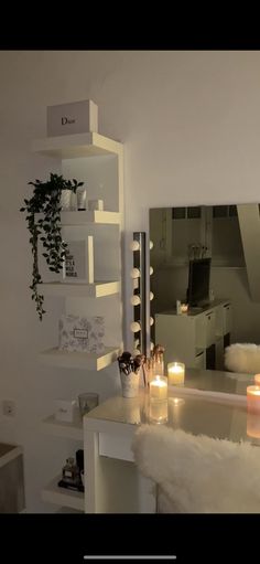 candles are lit in front of a mirror on the wall next to a white desk