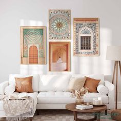 a living room filled with white furniture and pictures on the wall above it's coffee table