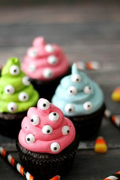 some cupcakes with googly eyes and candy on top are sitting on a table