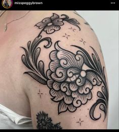 a woman's shoulder with black and white flowers on it, in the middle of her arm