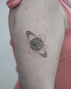 a woman's arm with a small tattoo on the back of her shoulder and an object in the middle