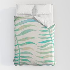 a bed with a green and white comforter on top of it next to a pillow