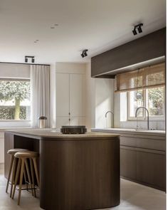 a kitchen with two stools in front of an island counter and window behind it