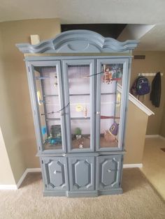 a blue china cabinet with glass doors in a living room next to a carpeted floor