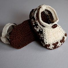 two knitted baby shoes sitting on top of a white table next to each other