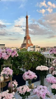 the eiffel tower is in the distance with pink flowers on tables around it