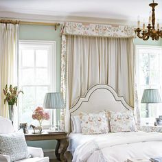 a white bed sitting in a bedroom next to two lamps and a table with flowers on it