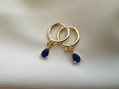 Sapphire blue gold plated hoop earrings with beautiful dangly blue cubic zirconia charm Gold plated brass hoops Hoop size approximately 14mm Charm size approximately 5mm Every order comes in our luxury matt frosted recyclable logo pouch, which are also available to purchase separately for any extra pieces you may want to store with style. Gift wrap sets (box & faux leather pouch)  are available at checkout and available to buy separately. Blue Hoop Earrings Gold Plated, Blue Cubic Zirconia Hoop Earrings As Gift, Blue Cubic Zirconia Hoop Earrings For Gift, Blue Gold-plated Hoop Earrings For Pierced Ears, Gift Sapphire Hoop Earrings, Blue Dangle Huggie Earrings As Gift, Sapphire Hoop Earrings As Gift, Blue Huggie Earrings As Gift, Gold Jewelry Earrings