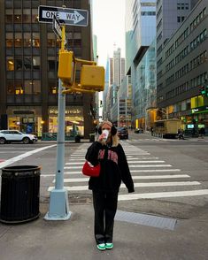 a woman walking down the street wearing headphones and talking on her cell phone, with buildings in the background