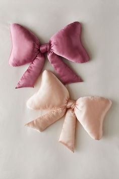 three satin bows on white surface with one pink and the other light pink in color