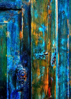 an old wooden door with peeling paint and rust on the doors, painted in blue and yellow