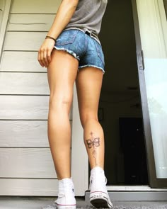 a woman with tattoos on her legs standing in front of a door