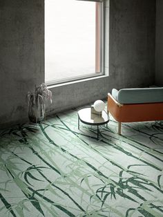 a room with a bed, coffee table and plant on the floor in front of a window