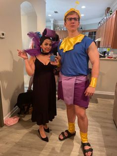 a man and woman in costume posing for the camera with one holding a cell phone