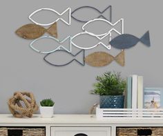 an assortment of metal fish mounted to the wall above a dresser with baskets on it