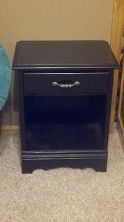 a black night stand next to a blue chair in a room with carpeted floor