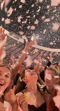 some people are throwing confetti in the air at a concert or show with their hands up