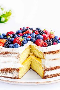 a cake with white frosting and fresh berries on top is cut in half to show the layers