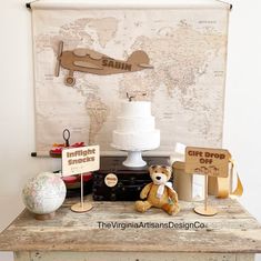 a table topped with a cake and two small teddy bears next to a world map