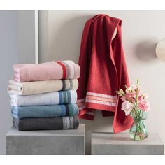 towels are stacked on top of each other next to a vase with flowers