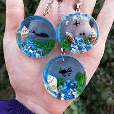 three glass caballons with sea creatures in them are held by someone's hand