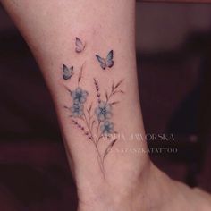 a woman's foot with blue flowers and butterflies on the side of her leg