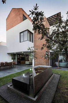 a modern house with an outdoor fire pit in the front yard and patio area on the other side