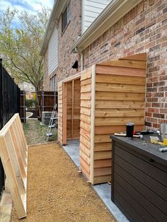 an outdoor storage shed built into the side of a brick building with wood slats