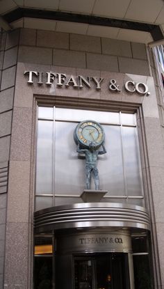 there is a clock that is on the building's front door and it says tiffany & co