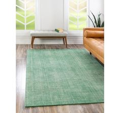 a green rug in a living room next to a couch